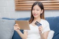 Young asian woman smiling holding credit card shopping online with tablet computer buying and payment. Royalty Free Stock Photo