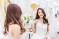 Young asian woman smiling and trying on wedding dress in a shop, asian bride look the mirror for beauty, Royalty Free Stock Photo