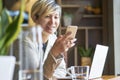 Young Asian woman smiling using smart phone and laptop at coffee shop Royalty Free Stock Photo