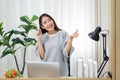 Young asian woman snapping finger while touching her temples with a pen. Enjoy studying at home with a textbook from university