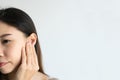 Young Asian woman with sore ear suffering from otitis over white background. Girl touch her ear with pain. Ear problem