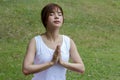 Young asian woman in sportswear meditating while sitting in lotus pose on yoga mat