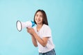 Young Asian woman standing on a blue background and hand touches on mouth with yelled for something. Royalty Free Stock Photo