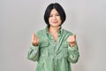 Young asian woman standing over white background doing money gesture with hands, asking for salary payment, millionaire business Royalty Free Stock Photo