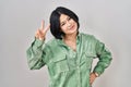 Young asian woman standing over white background smiling looking to the camera showing fingers doing victory sign Royalty Free Stock Photo