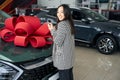 Young asian woman stands in front car with gift bow