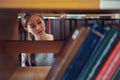 Young Asian woman student reaching for book on bookshelf in library Royalty Free Stock Photo