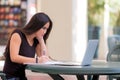 Young asian woman student sitting at table working with laptop c