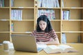 Young Asian woman student study and take notes with book in library. F Royalty Free Stock Photo