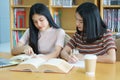 Young Asian woman student study and take notes with book in library. F Royalty Free Stock Photo