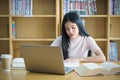 Young Asian woman student study and take notes with book in library. F Royalty Free Stock Photo