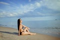 Young Asian woman sunbathing applying sunscreen at beach looking sea on a summer Royalty Free Stock Photo