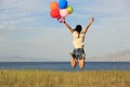 Young asian woman on sunset grassland with colored balloons Royalty Free Stock Photo