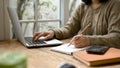 A young Asian woman taking notes on her notebook and using her laptop at a coffee shop Royalty Free Stock Photo