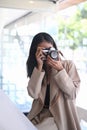 A young Asian woman taking photo with digital camera at her workstation. Royalty Free Stock Photo