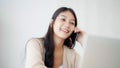 Young asian woman talking mobile smartphone while working on computer laptop on desk Royalty Free Stock Photo