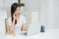 Young asian woman talking phone and work from home with laptop computer, freelance using notebook to internet online. Royalty Free Stock Photo