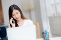 Young asian woman talking phone and work from home with laptop computer. Royalty Free Stock Photo