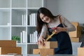 Young asian woman taping up a cardboard box in home office SME e-commerce business, relocation and new small business Royalty Free Stock Photo