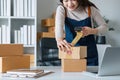 Young asian woman taping up a cardboard box in home office SME e-commerce business, relocation and new small business Royalty Free Stock Photo