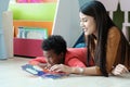 Young asian woman teacher and African boy in kindergarten classroom, preschool, elementary education concept