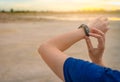 Young Asian woman touching smart band after running in the morning. Wearable computer. Heart rate monitor bracelet. Fitness device Royalty Free Stock Photo