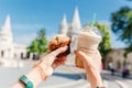 asian woman tourist drinking frappe sweet cold coffee and tasty muffin at the Budapest city street near Fisherman Bastion.