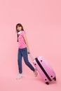 Young asian woman tourist with pink suitcase on pink background. The concept of at airports