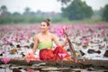 Young Asian women in Traditional dress in the boat and pink lotus flowers in the pond. Royalty Free Stock Photo