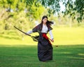 Young asian woman in traditional kimono trains fighting techniques with katana sword samurai warrior girl