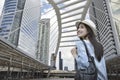 Young asian woman traveler with a backpack on her shoulder walking on pathway bridge over modern city tower in Bangkok, Thailand,