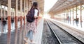Young asian woman traveler with backpack in the railway, Backpack and hat at the train station with a traveler, Travel concept. Royalty Free Stock Photo