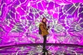 Young asian woman traveler posing with neon colored lights in background.