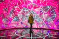 Young asian woman traveler posing with neon colored lights in background.