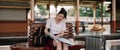 young asian woman traveler sitting with map choose where to travel and bag waiting for train at train station, summer Royalty Free Stock Photo