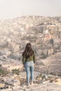 Young Asian woman traveller standing on stone and enjoying top view of Amman capital city of Jordan, Arab