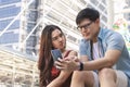 Young asian woman unhappy and angry while boyfriend paying no attention to her and busy using his mobile phone during a date.