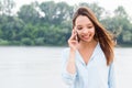 Young Asian woman uses smartphone, talking on phone and smiling on nature Royalty Free Stock Photo