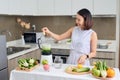 Young Asian woman using blender to make green smoothie in kitchen Royalty Free Stock Photo