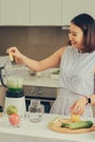 Young Asian woman using blender to make green smoothie in kitchen Royalty Free Stock Photo
