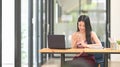 Young Asian woman is using a computer laptop while sitting at the wooden working desk Royalty Free Stock Photo