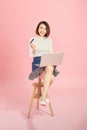 Young Asian woman using credit card to payment online with her laptop. Isolated on pink background Royalty Free Stock Photo