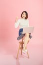 Young Asian woman using credit card to payment online with her laptop. Isolated on pink background Royalty Free Stock Photo