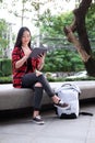 Young Asian woman using laptop computer while sitting outdoors in urban modern city in the evening Royalty Free Stock Photo