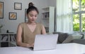 Asian woman using laptop at home, looking at screen, chatting, reading or writing email, sitting on desk Royalty Free Stock Photo