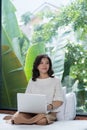 Young Asian woman using latop while sitting on bed