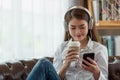 Young Asian woman using mobile phone and holding a hot cup of coffee, happy and relaxing time Royalty Free Stock Photo