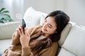 Young asian woman using mobile smartphone in living room Royalty Free Stock Photo