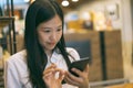 Young Asian woman using phone at a coffee shop happy and smile. Royalty Free Stock Photo