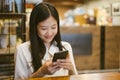 Young Asian woman using phone at a coffee shop happy and smile. Royalty Free Stock Photo